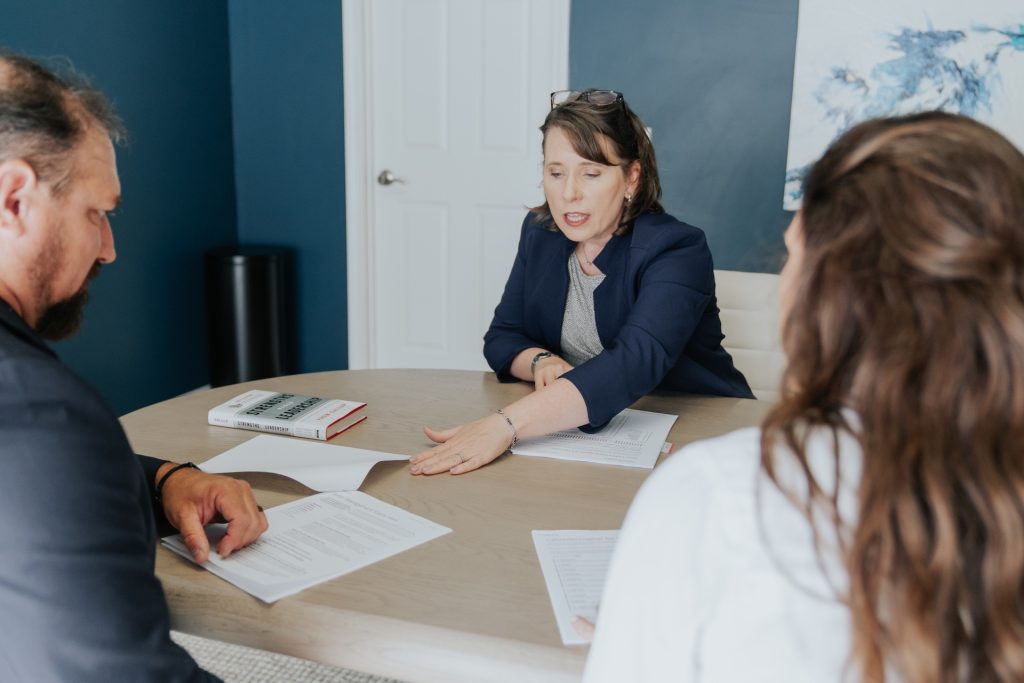 People gathered around a table discussing paperwork at a leadership coaching meeting